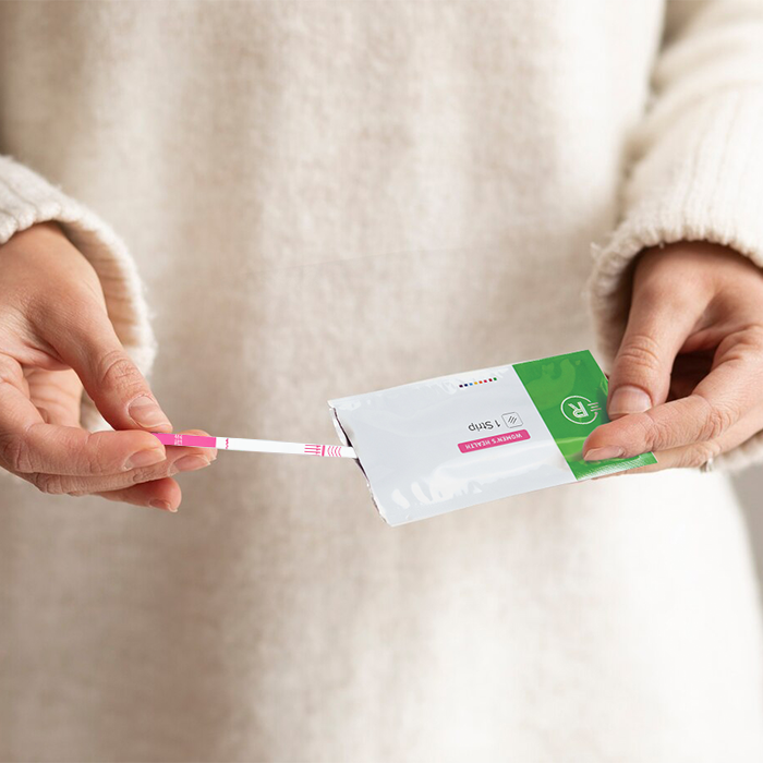 hCG Pregnancy Test Strip woman holding strip and open pouch