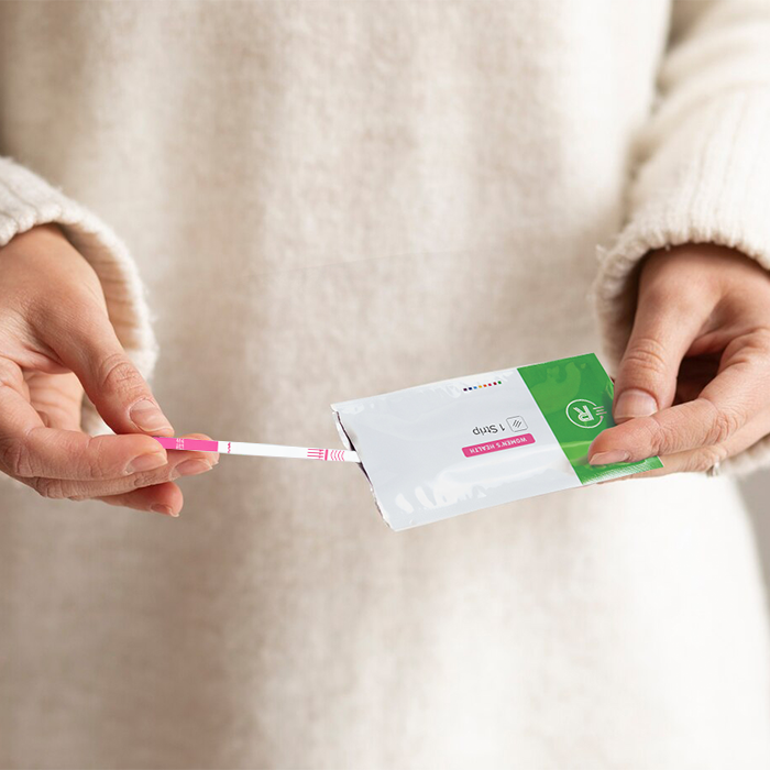 Rapid Response Pregnancy Test Strip person holding test strip and pouch